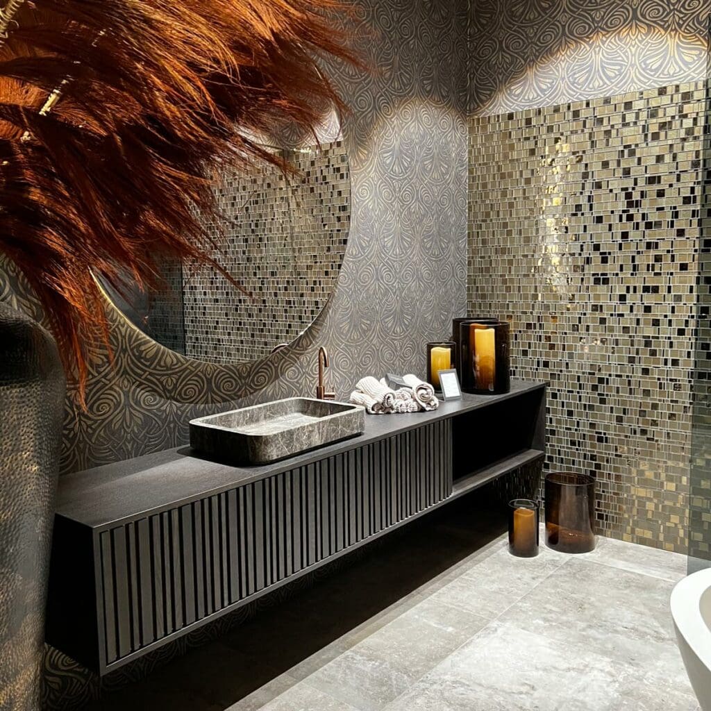 Schickes Badezimmer mit Mosaikfliesen und rundem Spiegel