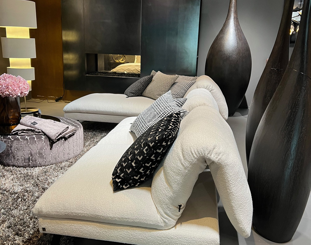 Modernes Wohnzimmer mit cremefarbenem Sofa, gemusterten Kissen und dunklen Skulpturen.