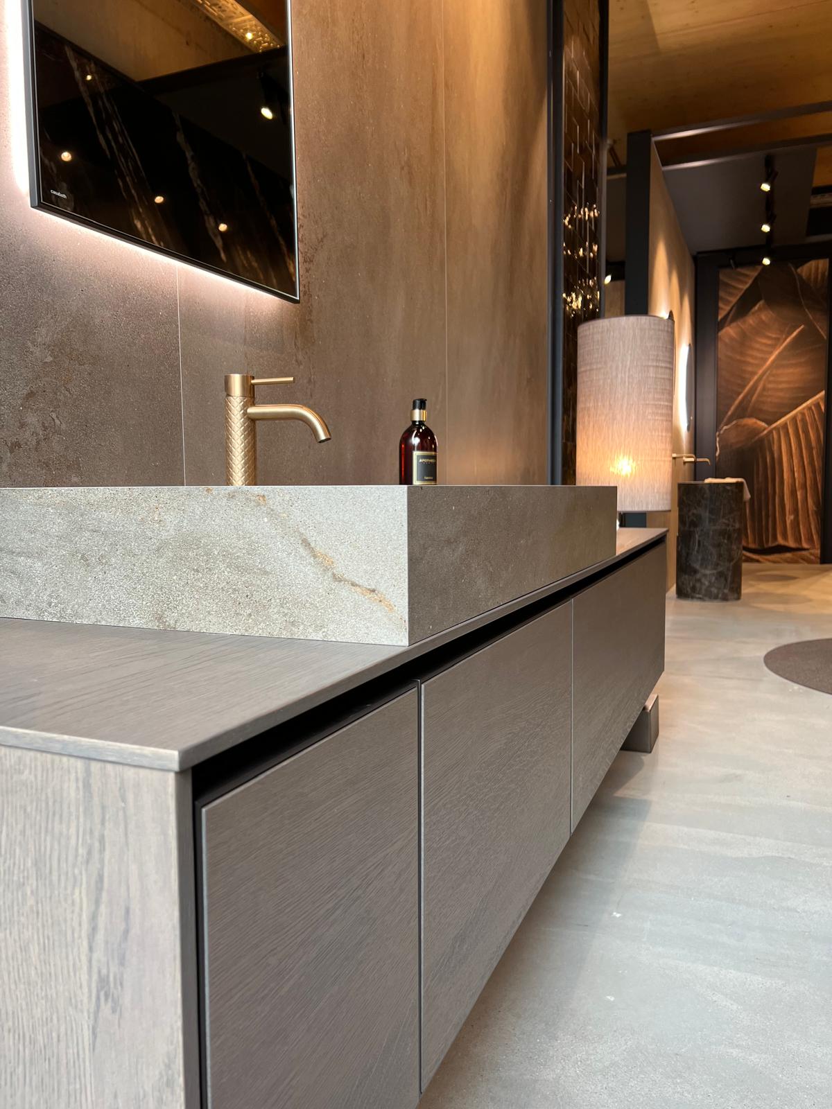 Modernes Badezimmer mit Holz-Waschtisch, goldener Armatur und beleuchtetem Spiegel.