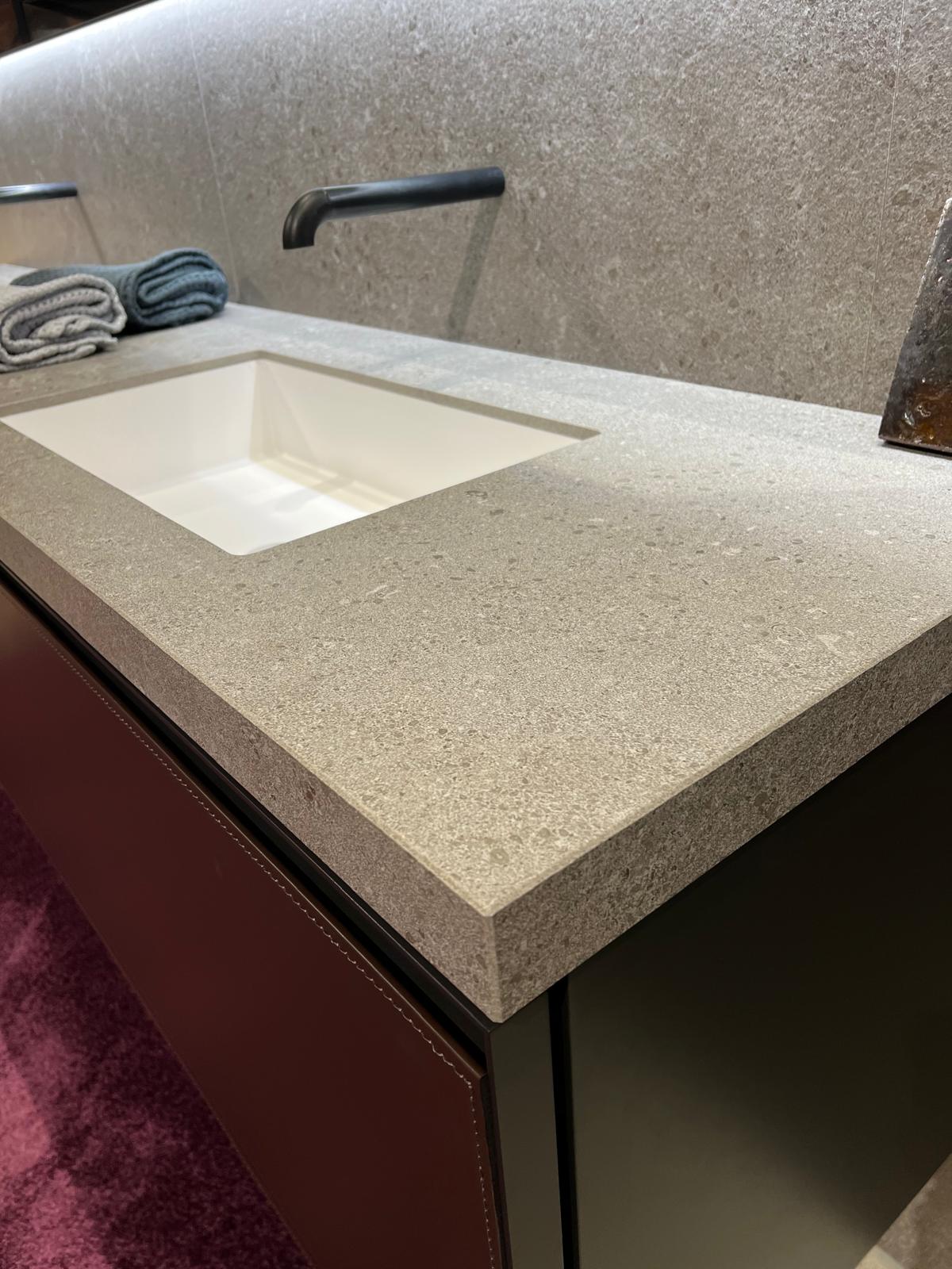 Graue Stein-Arbeitsplatte mit eingebautem rechteckigem Waschbecken und modernem Armaturendesign.