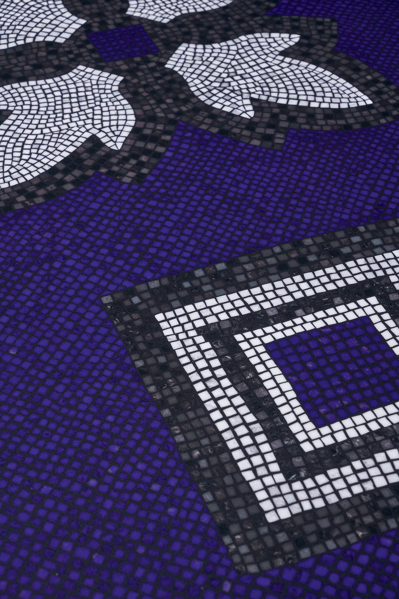 Ein violettes Mosaik mit weißen Blättern und quadratischen Mustern in Schwarz und Weiß