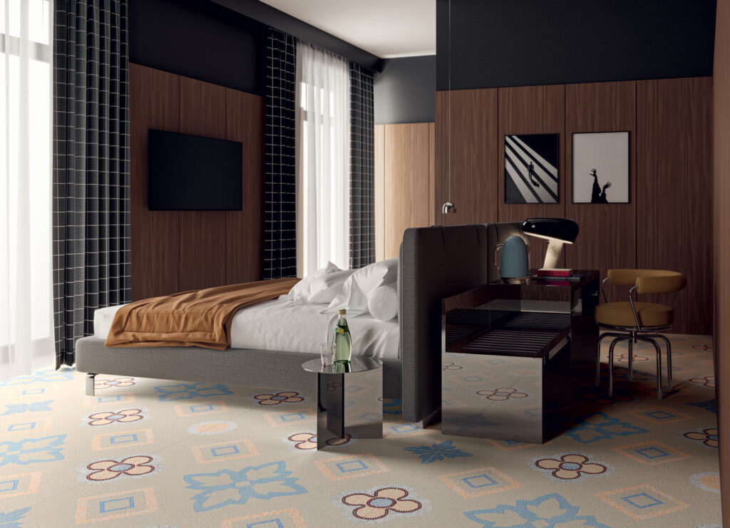Heller Boden mit großflächigen, farbenfrohen Mosaik-Ornamenten in Blumen- und Rautenform in einem modern eingerichteten Schlafzimmer.